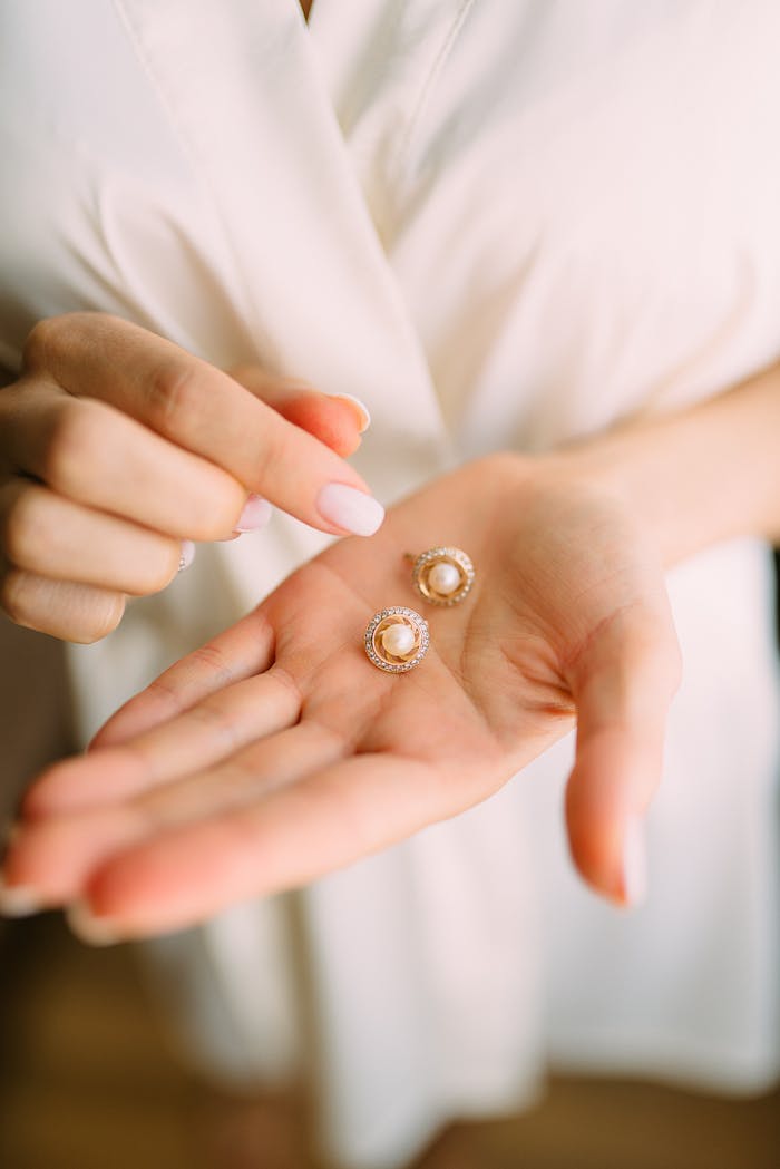 services-01 Close-up of elegant pearl earrings held in a hand, showcasing luxury jewelry.